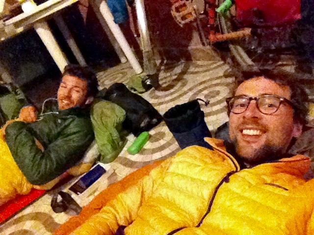 Nico and Dan, lying in sleeping bags, on mats, on the tiled floor of the bar. Both grinning at the camera.