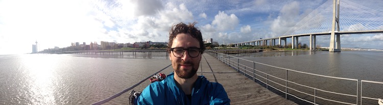 Dan in the foreground on a small pier, with Lisbon sprawling out in the background (panorama)