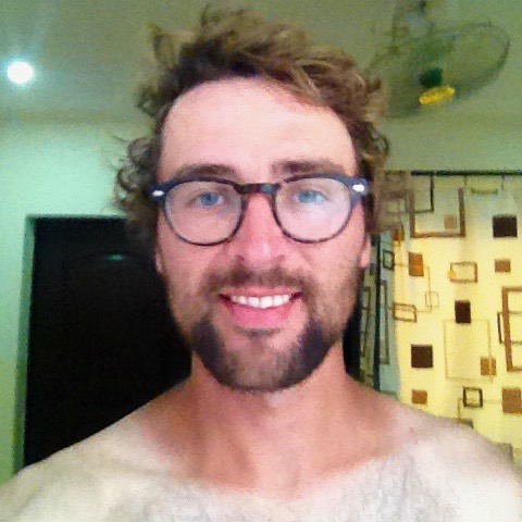 Portrait photo of Dan, with no top. His neck is extremely tanned, but the tan immediately turns to white at his chest and shoulders.