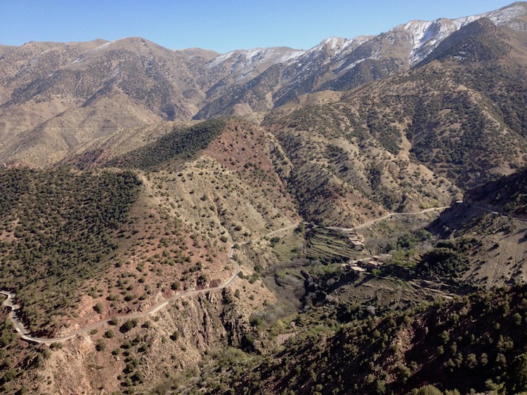 A photo taken from very high up, looking down on various mountainous formations, with a small road snaking across the image.