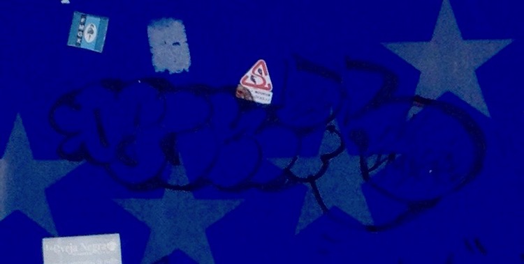 Close-up of the Portuguese border sign, showing a graffiti 'tag', which is shaped like a phallus