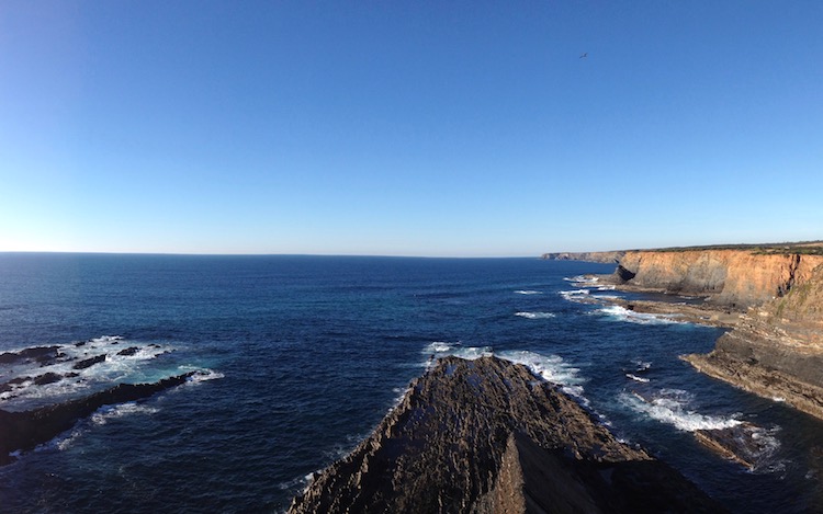 Semi-panorama, showing more golden cliffs, deep blue sea and blue skies.