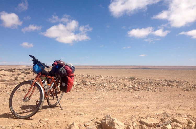 Dan's bike parked in the foreground, with nothing but flat, rocky sand stretching all around and into the distance.