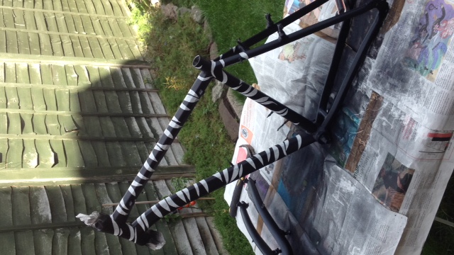 Black bike covered in masking tape stripes (more like a zebra)