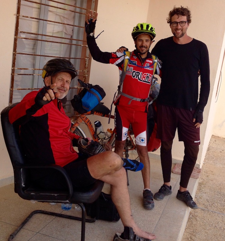 Tim, Mohamed and Dan outside a building, smiling. All in bike gear.